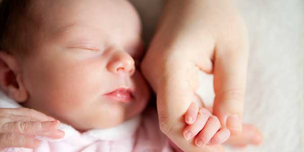 Newborn baby holding mother's hand